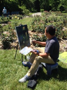 A plean air artist captures a yellow rose on canvas.